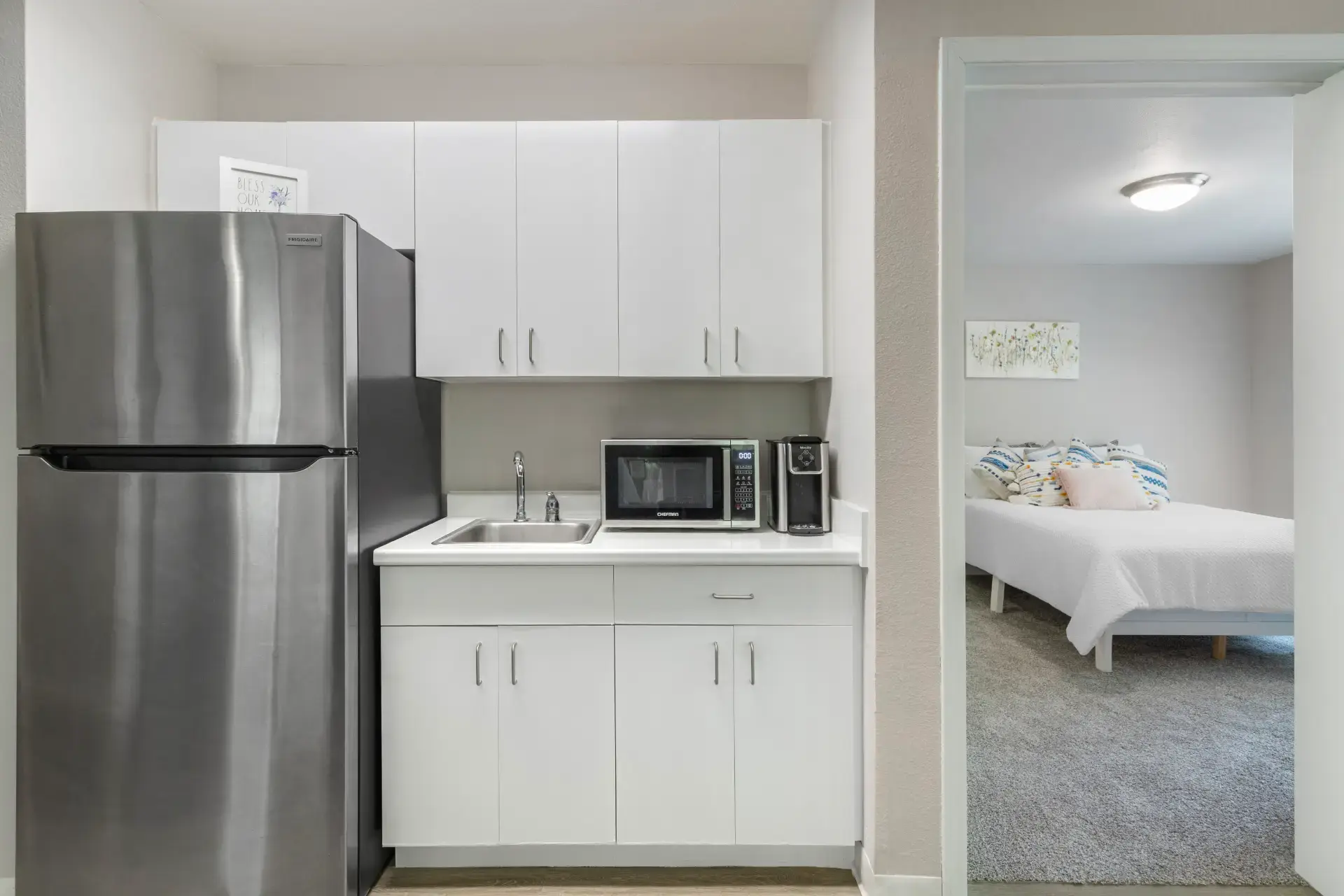 Kitchen with view of microwave and sink and entry to bedroom.