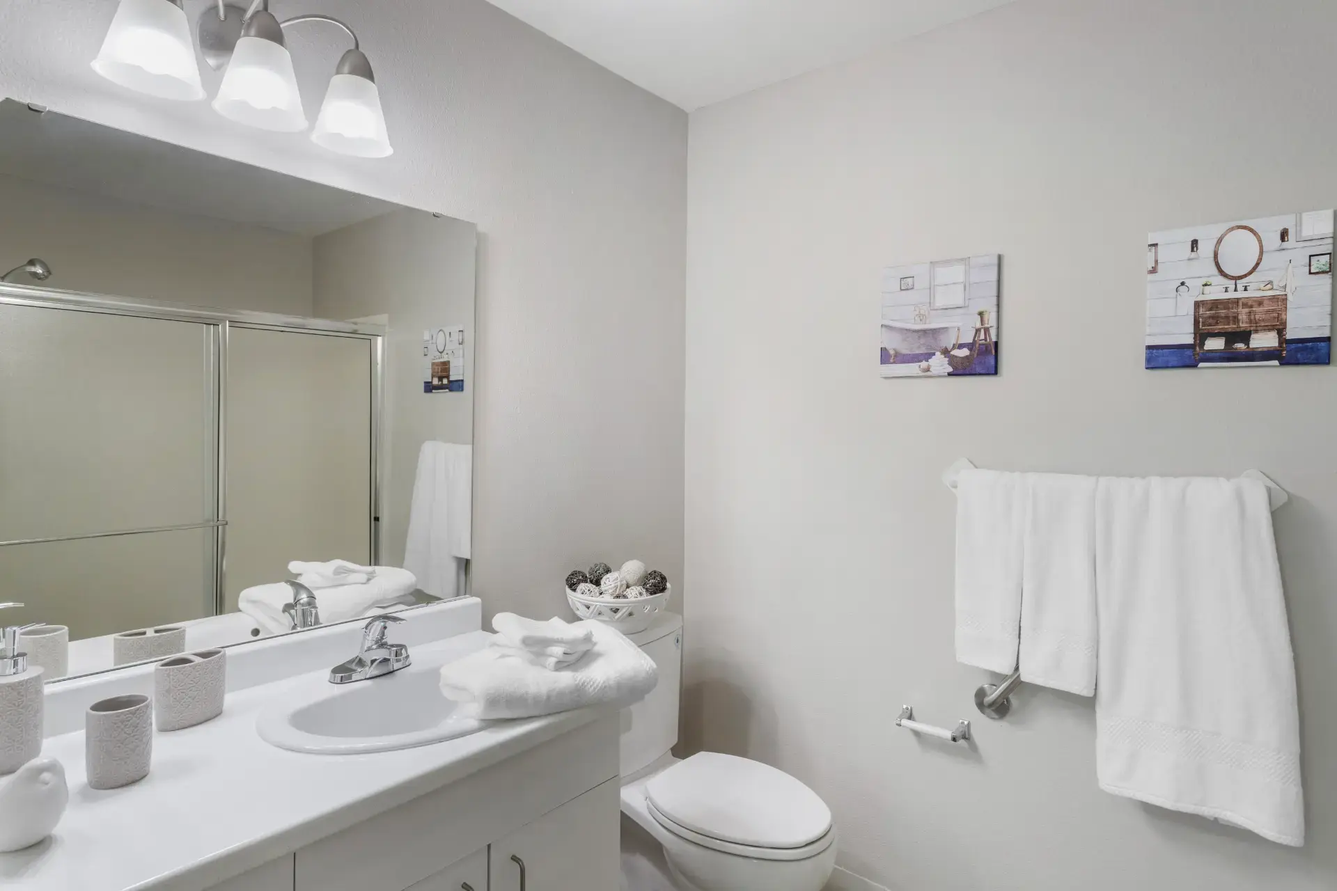 Bathroom with towels and artwork on walls.
